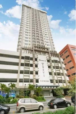 a large white building with cars parked in front of it at Laureano di trevi tower condominium Corporation in Manila