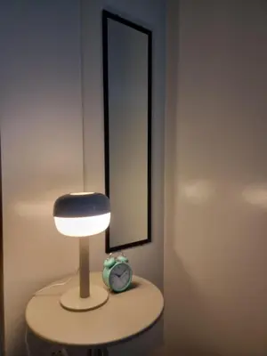 a lamp on a table with a clock and a mirror at One Palm Tree Villas in Manila