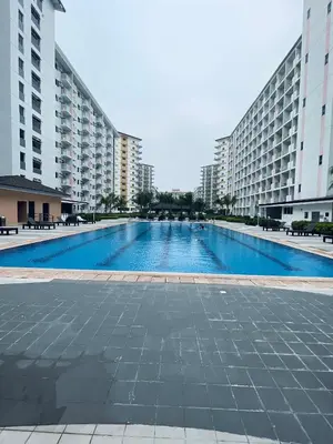 a large swimming pool in the middle of two buildings at Field Residences Condo Hotel Near Manila Airport in Manila