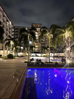 a large swimming pool in a city at night at Field Residences Condo Hotel Near Manila Airport in Manila