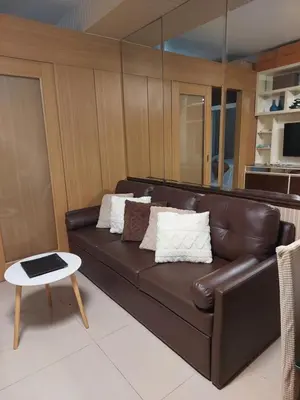 a brown leather couch in a living room with a table at Executive Suite 519A at Shell Residence by GK Condotel in Manila