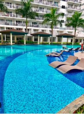 a swimming pool with lounge chairs and a large building at Suite 1443D at Shell Residence by GK Condotel in Manila