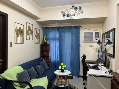 a living room with a blue couch and a table at BayFront 1BR Condo in Pasay with FREE Wi-Fi, Netflix, Pool Access & Gym, Near NAIA Airport, MOA, OKADA, CCP & PICC in Manila