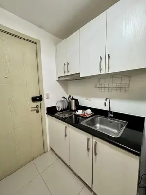 a kitchen with white cabinets and a sink and a door at Jazz Residences Tower B in Manila