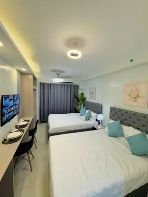 a hotel room with two beds and a desk at Budget Condo near Airport and Mall of Asia in Manila
