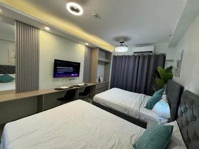 a hotel room with two beds and a desk with a tv at Budget Condo near Airport and Mall of Asia in Manila