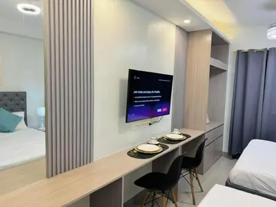 a hotel room with a desk with a tv on the wall at Budget Condo near Airport and Mall of Asia in Manila