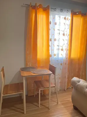 a table and a chair in a room with curtains at Tulip Garden Condominium Southwoods in Biñan