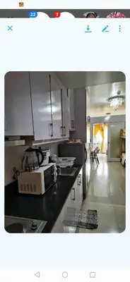 a kitchen with white cabinets and a black counter top at Shell Condotel MOA Pasay in Manila