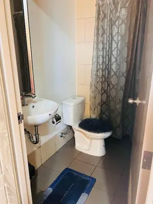 a bathroom with a toilet and a sink and a shower at Tulip Garden condo in Biñan