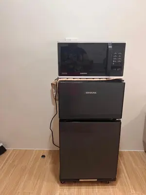 a microwave oven sitting on top of a refrigerator at Tulip Garden condo in Biñan