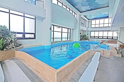 a large swimming pool in a large room with windows at Spacious Cozy Corner in Manila