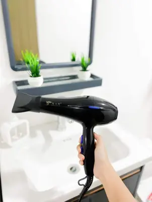 a person holding a hair dryer in front of a desk at The Tropical Suite SMDC Hope Residence in Trece Martires
