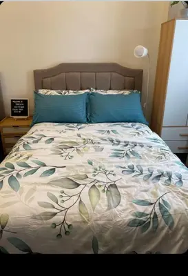 a bed with blue pillows and a floral bedspread at The Tropical Suite SMDC Hope Residence in Trece Martires