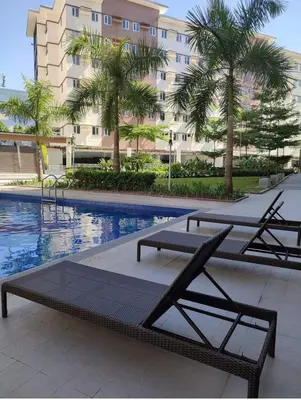 a swimming pool with two lounge chairs and a building at The Tropical Suite SMDC Hope Residence in Trece Martires