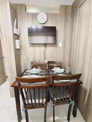 a dining room table with chairs and a clock on the wall at Escape To Paradise in Manila
