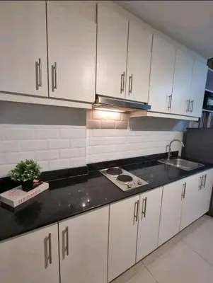 a kitchen with white cabinets and a sink at Cozy Room At Sea Residences in Manila