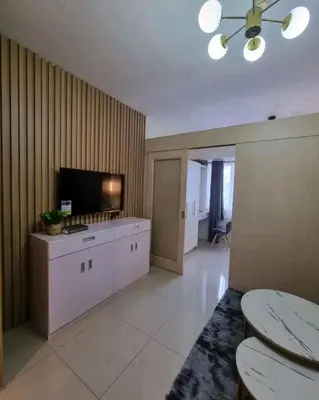 a large living room with a television and a table at Cozy Room At Sea Residences in Manila