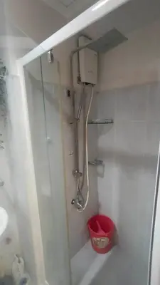 a bathroom with a shower with a red bucket at Cozy Room At Sea Residences in Manila