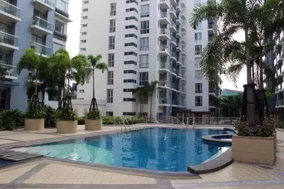 a swimming pool with palm trees in front of a building at Cozy Home Right Across International Airport Terminal 3 in Manila