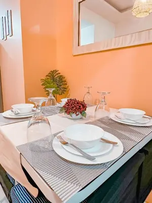a table with plates and wine glasses on it at Aeva's Cozy Stay in Manila
