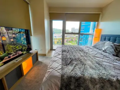 a bedroom with a large bed and a large window at Bayshore Resort Residences - Okada Manila in Manila
