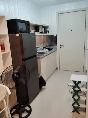 a kitchen with a refrigerator and a table with a fan at Condo sa south residences tower 3 in Manila