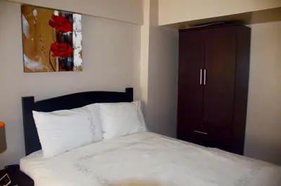 a bedroom with a white bed and a cabinet at Mondavi II Condo Unit 306 in Silang