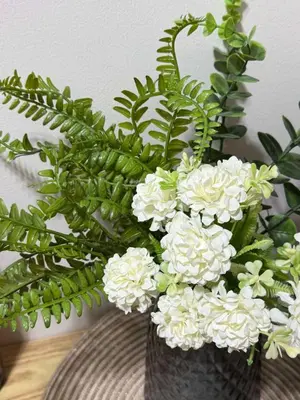 a vase filled with white flowers and green plants at R & A Enclave in Manila