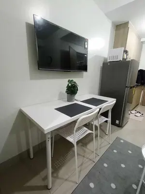 a white table and chairs with a tv on the wall at Cozy Home near Mall of Asia with WIFI and Netflix in Manila