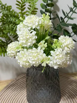 a black vase filled with white flowers on a table at R and A Enclave in Manila