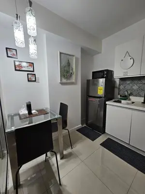 a small kitchen with a table and a refrigerator at The Bahamas & Maldives Suites by Azure Urban Resort Residences in Manila