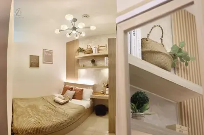 a small bedroom with a bed and a shelf at Cozy and Stylish Unit in Fame Residences in Manila
