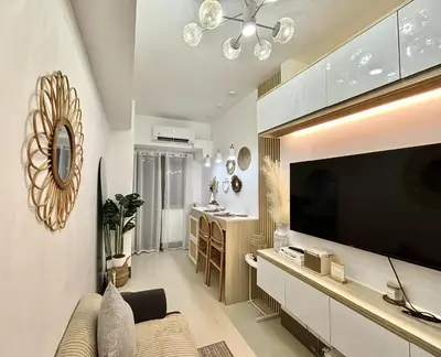 a living room with a large flat screen tv at Cozy and Stylish Unit in Fame Residences in Manila