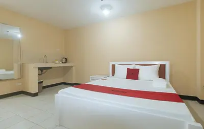 a bedroom with a large white bed with a red blanket at RedDoorz at MUBG Apartelle near Baclaran Church in Manila