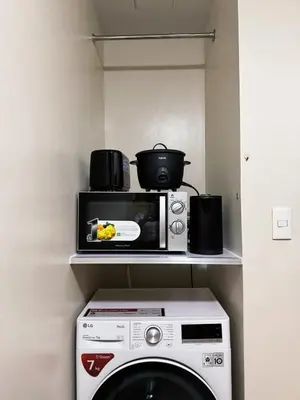 a microwave sitting on a shelf above a washing machine at Sleek & Chic One-Bedroom in Manila