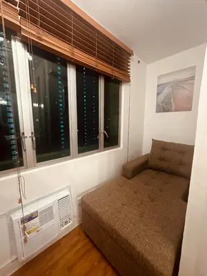 a bedroom with a bed and a window with a fan at EDSA Cozy 3BR near MRT w Netflix and Karaoke Fun in Manila