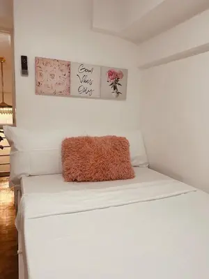 a white bed with a brown pillow on it at EDSA Cozy 3BR near MRT w Netflix and Karaoke Fun in Manila