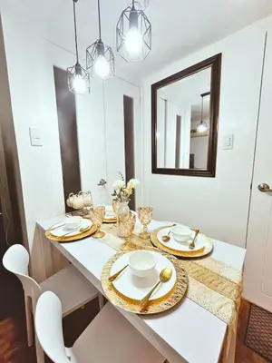 a dining room with a white table with chairs and a mirror at Cozy 2 BR 2 Bath Condo with Netflix and Karaoke near MRT EDSA in Manila