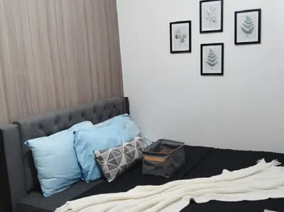 a bedroom with a bed with pillows and pictures on the wall at MOA - Aseana Pasay Condo in Manila