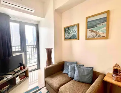 a living room with a couch and a television at Central Ortigas Condo in Manila