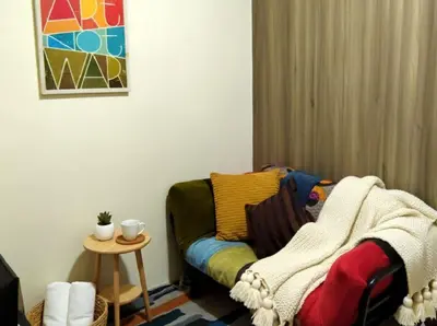 a living room with a couch with a blanket on it at SMDC Ortigas FAME in Manila