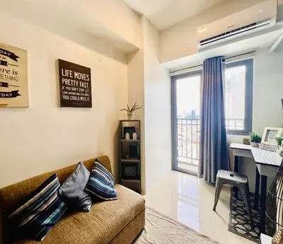 a living room with a couch and a desk at SMDC FAME in Ortigas in Manila