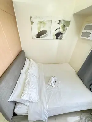 a bed with white sheets and a roll of toilet paper at Staycation at Field Residences Near Airport in Manila