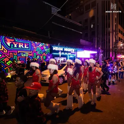 a group of people dressed in santa costumes walking down a street at night at Shore Residence a31 shortwalk Mall of Asia in Manila