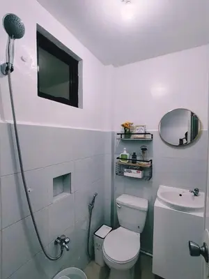 a white bathroom with a toilet and a mirror at Aki's Place Binangonan in Binangonan