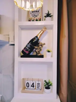 a shelf with a bottle of champagne and a clock at Aki's Place Binangonan in Binangonan