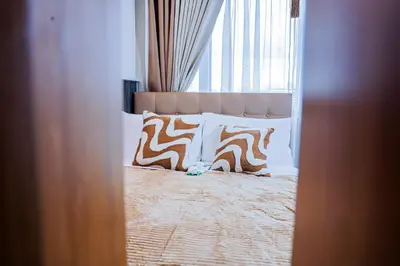 a bedroom with a bed with pillows and a window at Seventh Ave in Manila