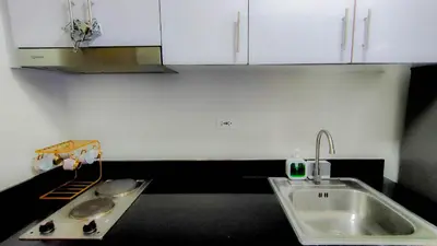a kitchen with a sink and white cabinets at Stylish Condo at Shore 2 Residences near MOA & Airport in Manila