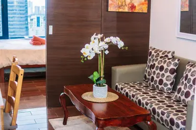 a living room with a table with a vase of flowers at Urban Charm Cozy Meet 51 Air Swim Gym Park 300Mb in Manila